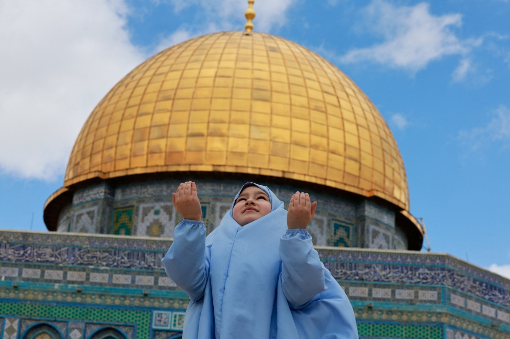 A Muslim woman prays next to the Dome of the Rock before the beginning of the first Friday prayers during Ramadhan on the Al Aqsa compound