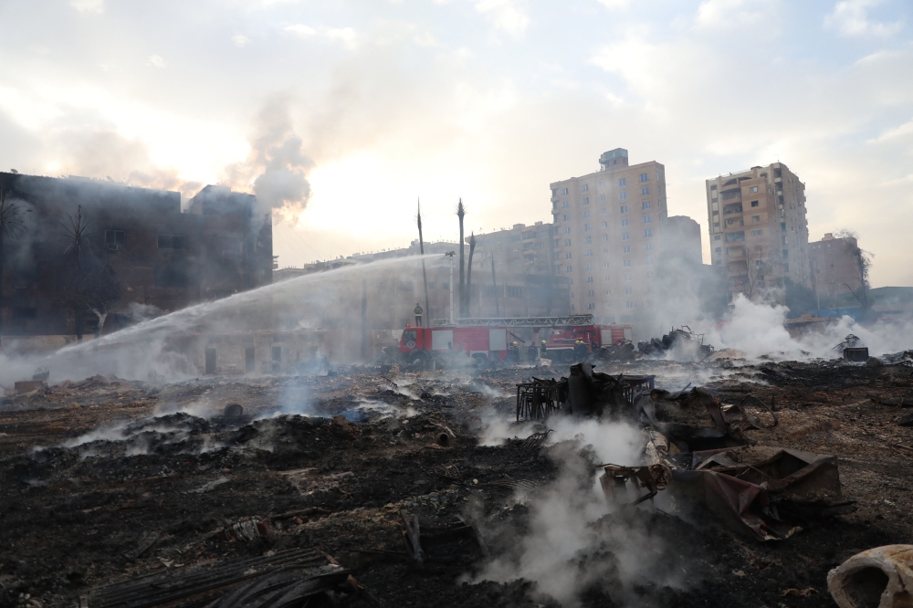 Firefighters cool the area still smouldering after a fire at the Al-Ahram Studio 
