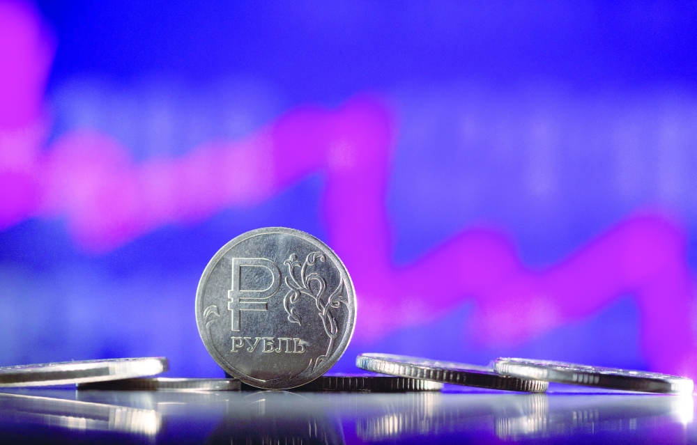 Illustration shows Russian Rouble coins are seen in front of descending stock graph. — Reuters