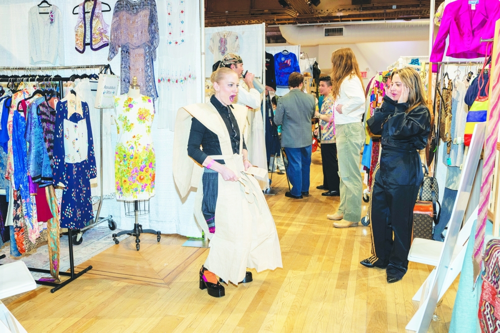 Kate McGuire, who runs the Instagram account @convertedcloset, cannot contain her excitement upon trying on a find at the Sturbridge Vintage Show in New York, March 14, 2024. (Hiroko Masuike/The New York Times)