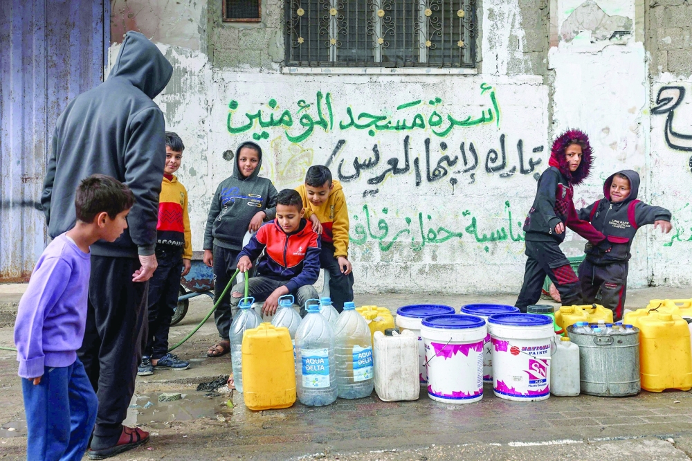 A boy fills water containers from a hose in Rafah in the southern Gaza Strip. — AFP 