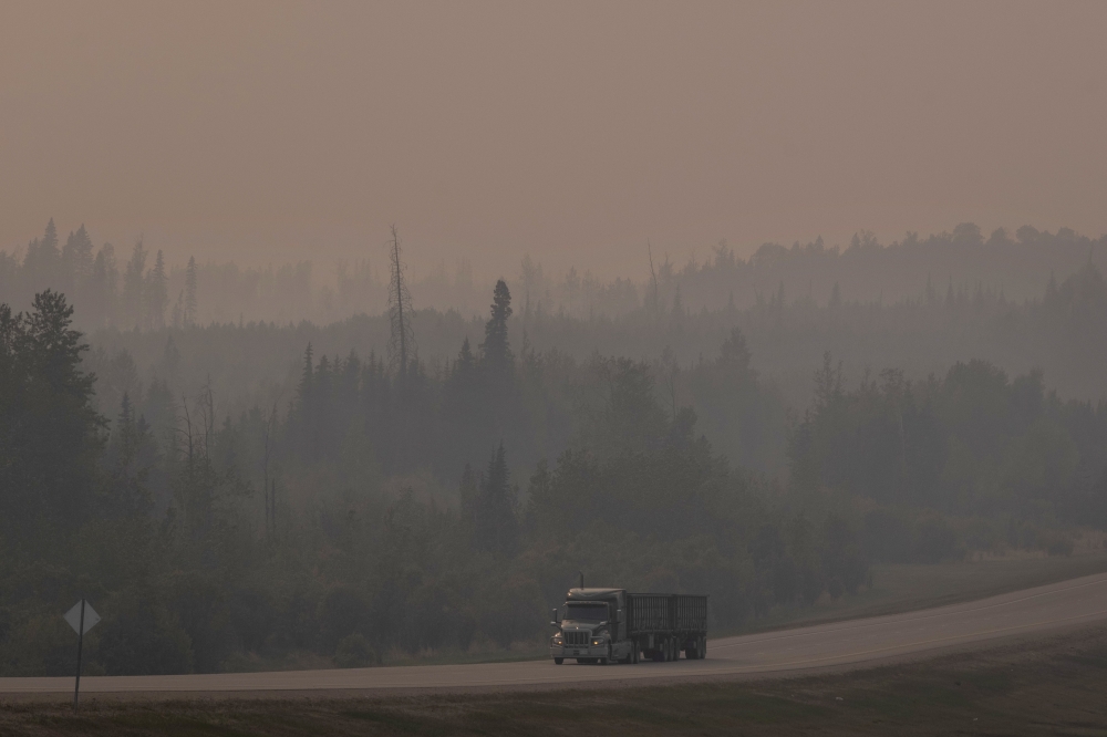 A thick layer of smoke from wildfires blankets a road in Fox Creek, Canada on May 18, 2023.