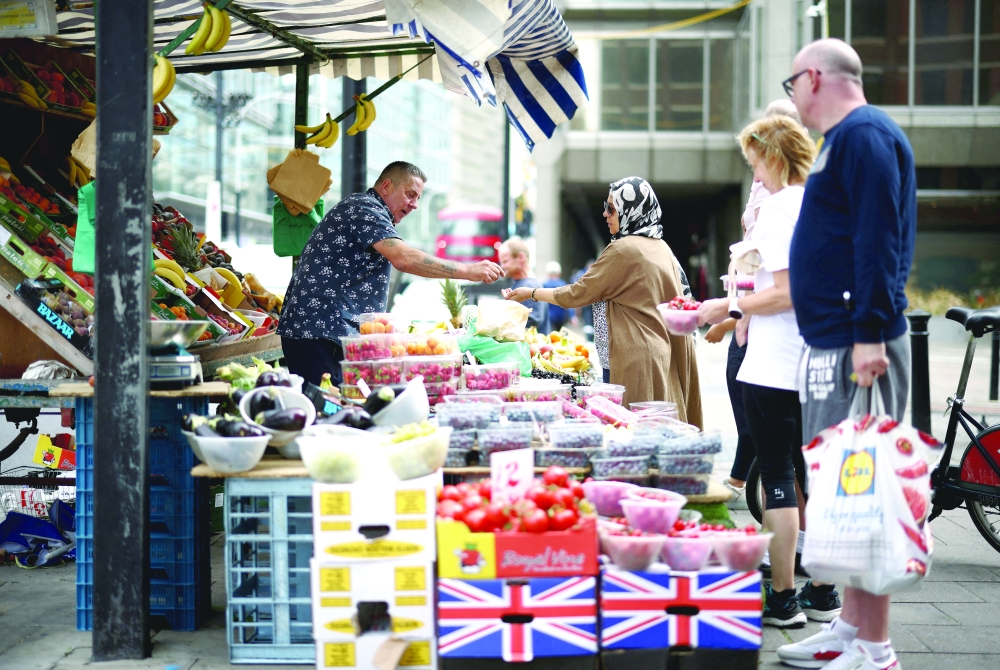 A person buys produce from a fruit and vegetable market stall in central London.  — Reuters