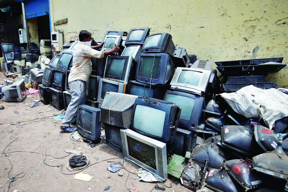 A scrap dealer piles up discarded TV sets before dismantling them at a scrap yard in Ahmedabad-REUTERS