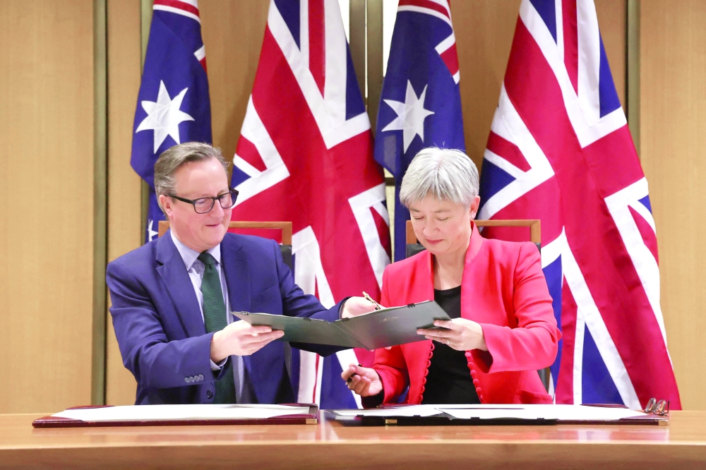 Britain's Foreign Secretary David Cameron participates in a signing ceremony with Australian Foreign Minister Penny Wong at Parliament House in Canberra. — AFP