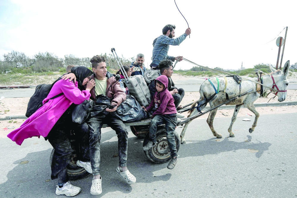 Displaced Palestinians fleeing from the area in the vicinity of Gaza City's al-Shifa hospital ride on a donkey-drawn cart as they arrive at the Nuseirat refugee camp in the central Gaza Strip. — AFP

