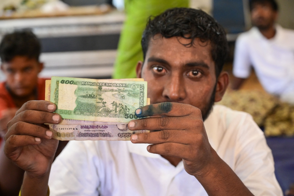 A newly arrived Rohingya refugee shows Bangladeshi banknotes at the former Red Cross Indonesia office building in Meulaboh