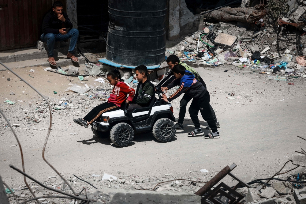Palestinian children play with a toy car on a street damaged by Israeli bombardment in Rafah in the southern Gaza Strip, amid ongoing battles between Israel and Hamas