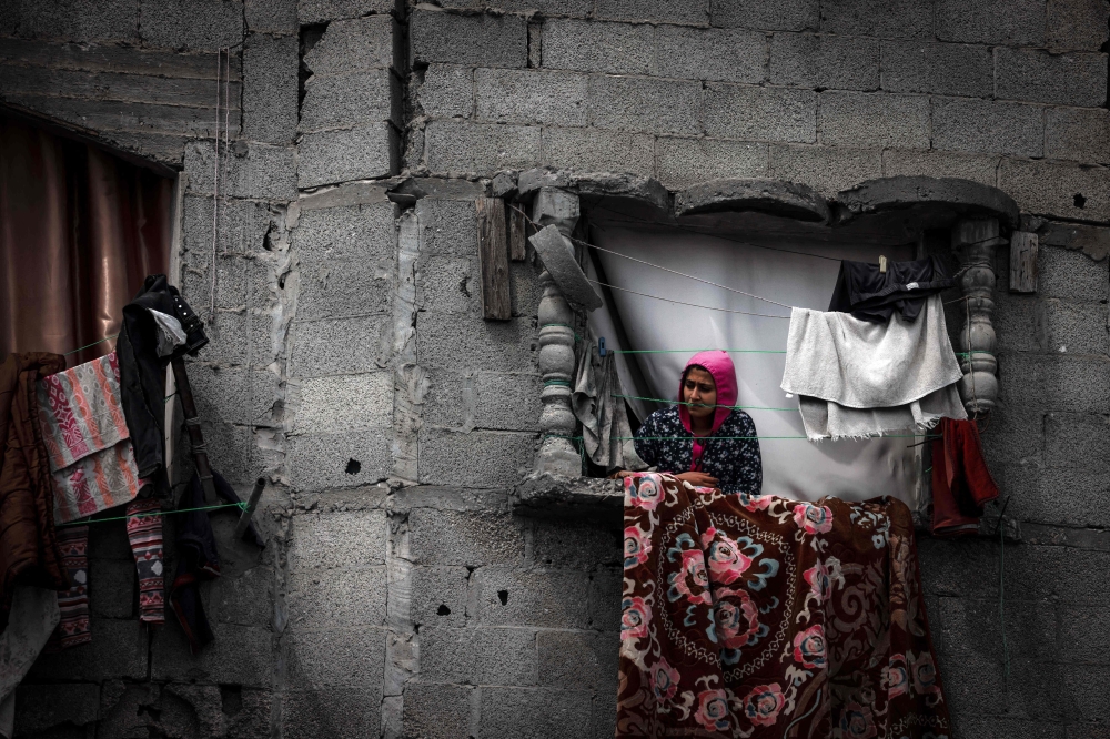 A Palestinian woman stands on the window of a building damaged by Israeli bombardment in Rafah in the southern Gaza Strip 