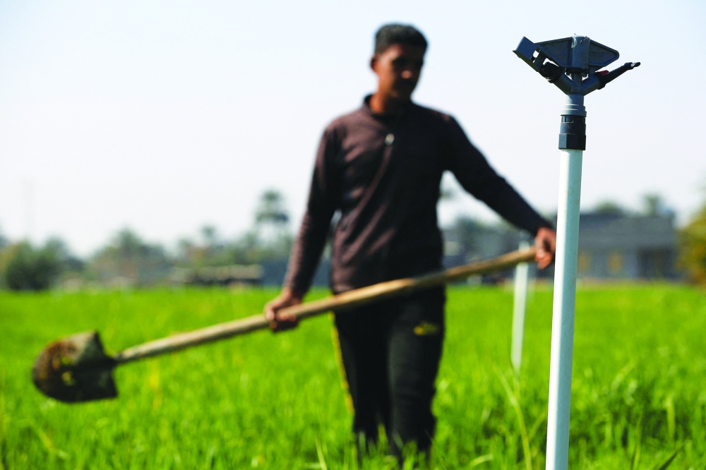 A farmer walks next to sprinklers, part of a new water management systems brought by the UN World Food Programme, on his farm in the village of al-Azrakiya, in Iraq's central province of Anbar, on February 22, 2024. Hundreds of Iraqi farmers benefited from new water management systems brought by the WFP. It uses automated sprinklers and drip irrigation to ensure scarce water is used in the most efficient way and not lost as run-off or evaporated under the blazing sun.