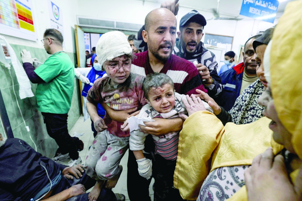 A man carries children injured in Israeli bombardment, at the al-Najjar hospital in Rafah. — AFP 