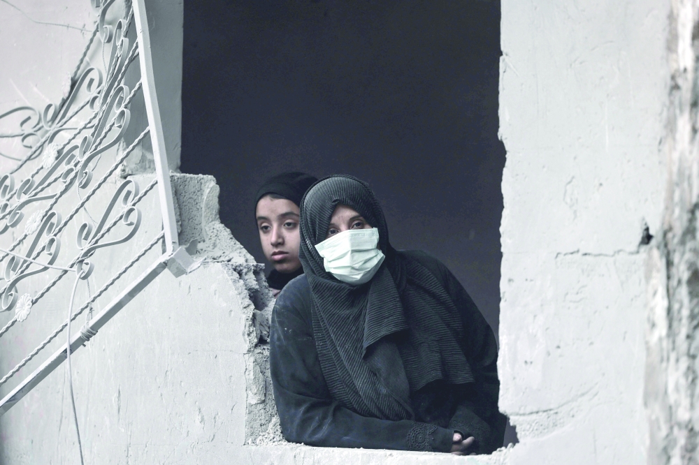 Palestinian women look out from the window of a building hit by overnight Israeli bombardment in Rafah. — AFP