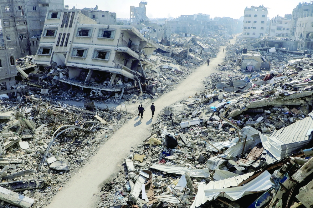 Palestinians walk past destroyed houses, amid the ongoing Israeli strikes, in Jabalia refugee camp. — Reuters 