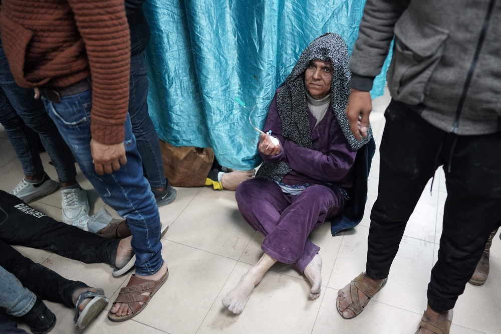 An injured Palestinian woman sits on the floor at a hospital in Zuwayda in the central Gaza Strip 
