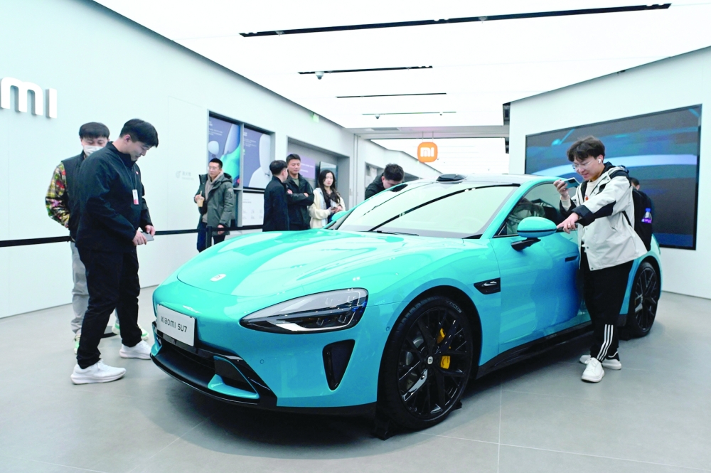 People look at a Xiaomi SU7 electric car displayed at a Xiaomi store in Beijing. - AFP

