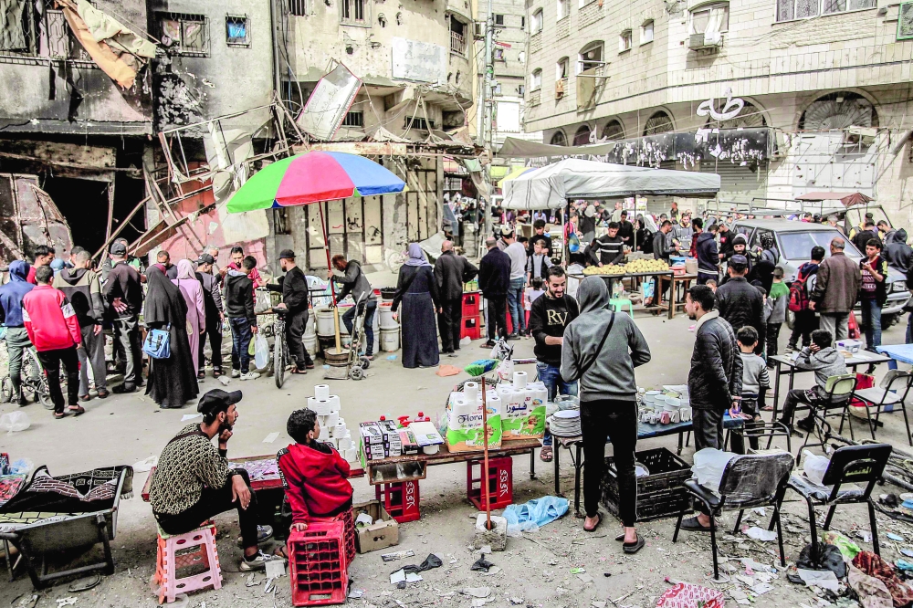 People shop from vendors in an open-air market amidst destruction in Gaza. - AFP