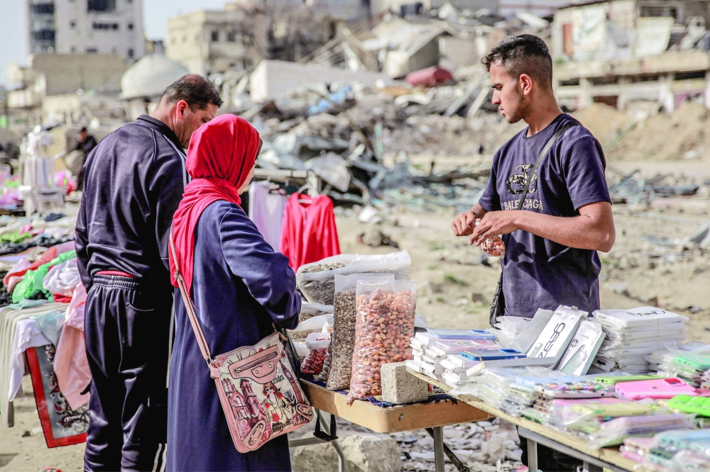 People shop from vendors in an open-air market amidst destruction in Gaza. - AFP