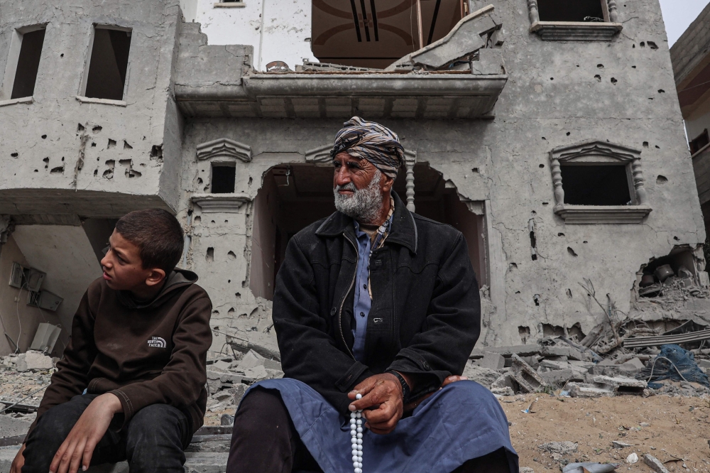 Palestinians inspect the damage to a building after overnight Israeli bombardment in Rafah