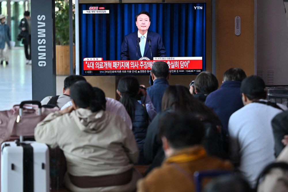 People watch live footage of South Korean President Yoon Suk Yeol delivering a speech on his medical reform plans, at a railway station in Seoul. — AFP 