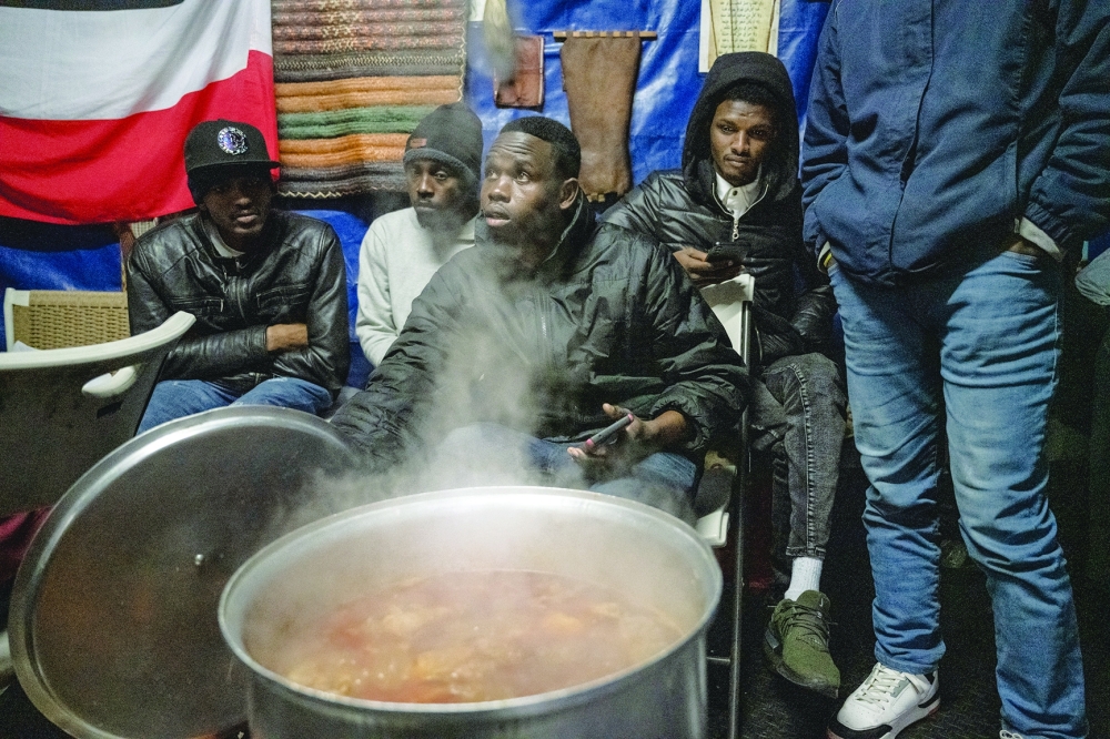 Lotfi Ibrahim, center, who was living in a shelter until he hit a 30-day limit and was forced to leave, helps to check on a pot of chicken cooking in a back yard near the Masjid At Taqwa mosque in the Bedford-Stuyvesant neighborhood of Brooklyn, on March 22, 2024. 