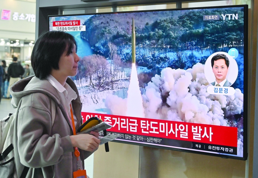 A woman walks past a television screen showing a news broadcast with file footage of a North Korean missile test, at a railway station in Seoul. — AFP 