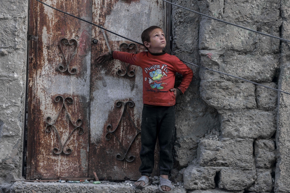 TOPSHOT - A Palestinian boy looks at a drone in the sky in the southern Gaza Strip city of Rafah on April 2, 2024, amid the ongoing conflict between Israel and Hamas. (Photo by MOHAMMED ABED / AFP)
