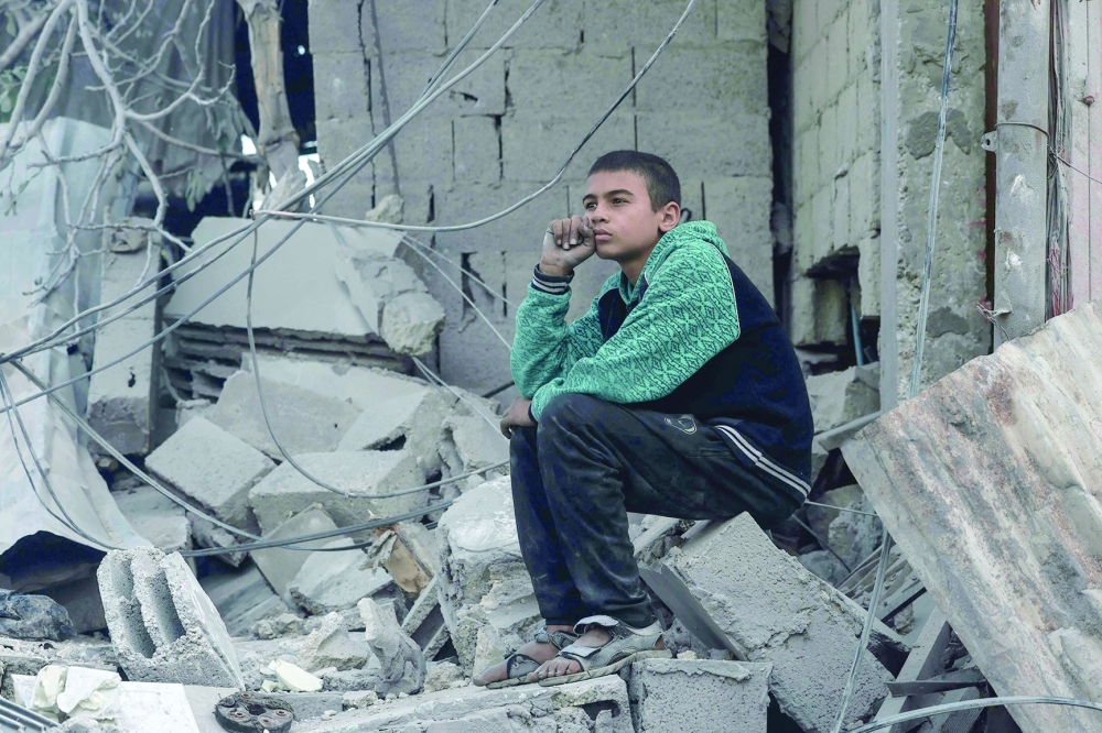 A Palestinian boy sits amid the rubble of a destroyed house in the southern Gaza Strip city of Rafah. — AFP 