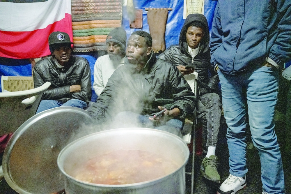 Lotfi Ibrahim, center, who was living in a shelter until he hit a 30-day limit and was forced to leave, helps to check on a pot of chicken cooking in a back yard near the Masjid At Taqwa mosque in the Bedford-Stuyvesant neighborhood of Brooklyn, on March 22, 2024.
