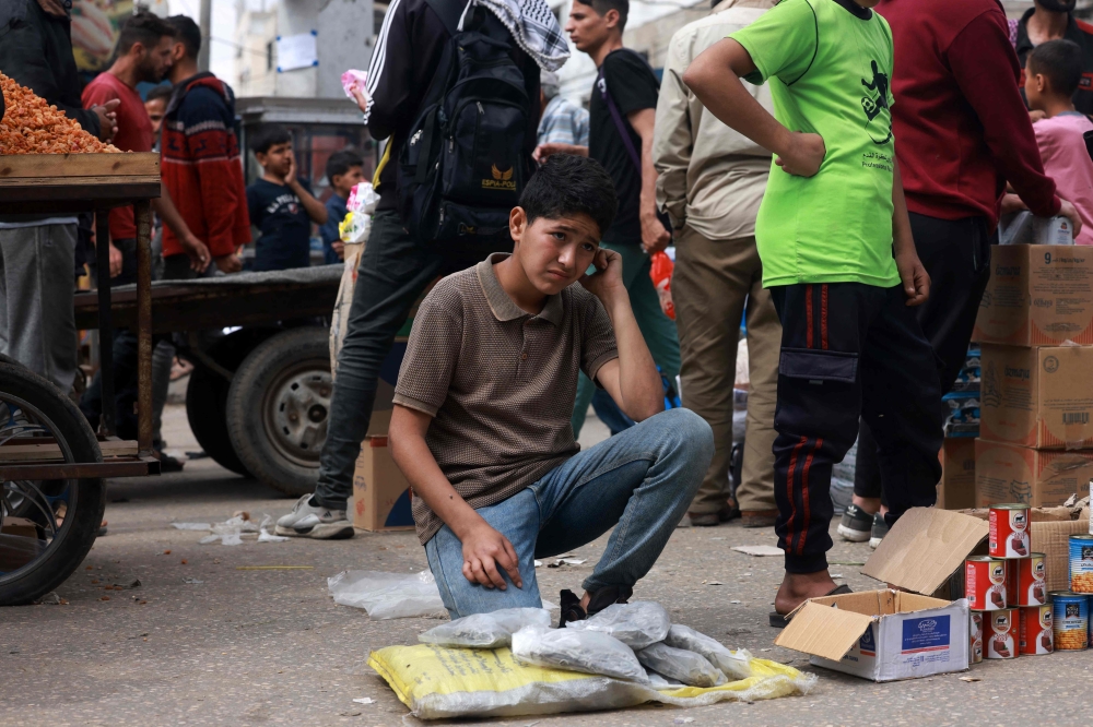 A Palestinian child sells food items in a market, in Rafah. — AFP 