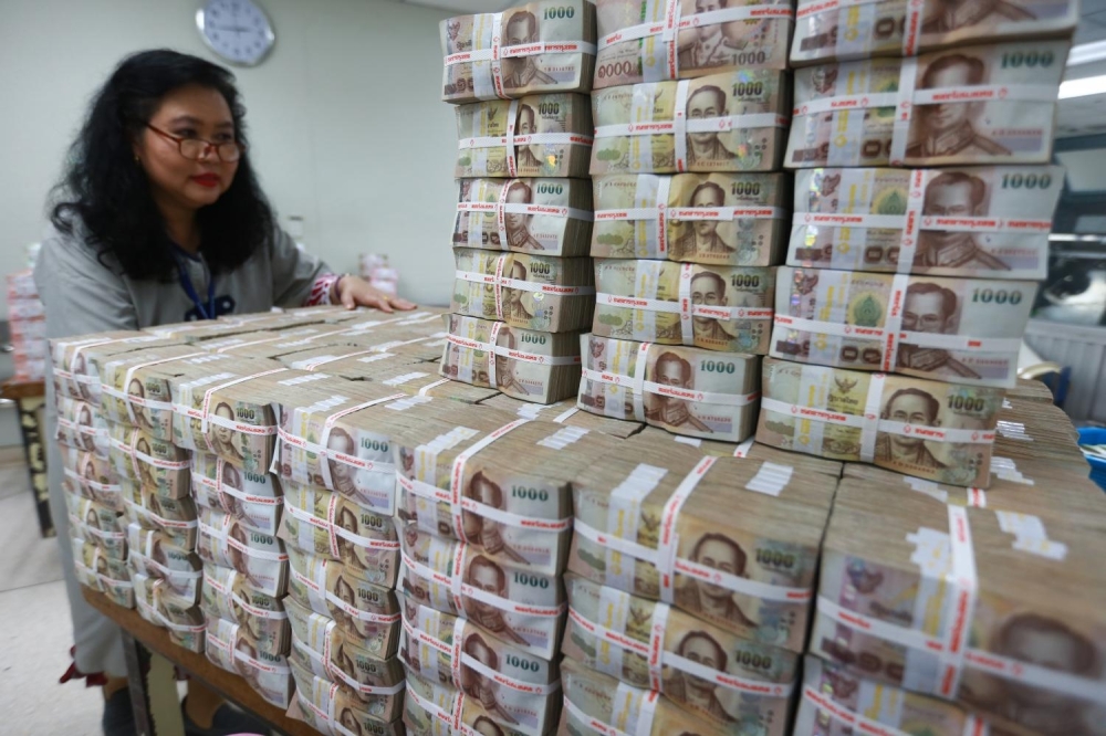 An employee pushes a stack of Thai Baht inside the Bank of Thailand headquarters in Bangkok. — Reuters