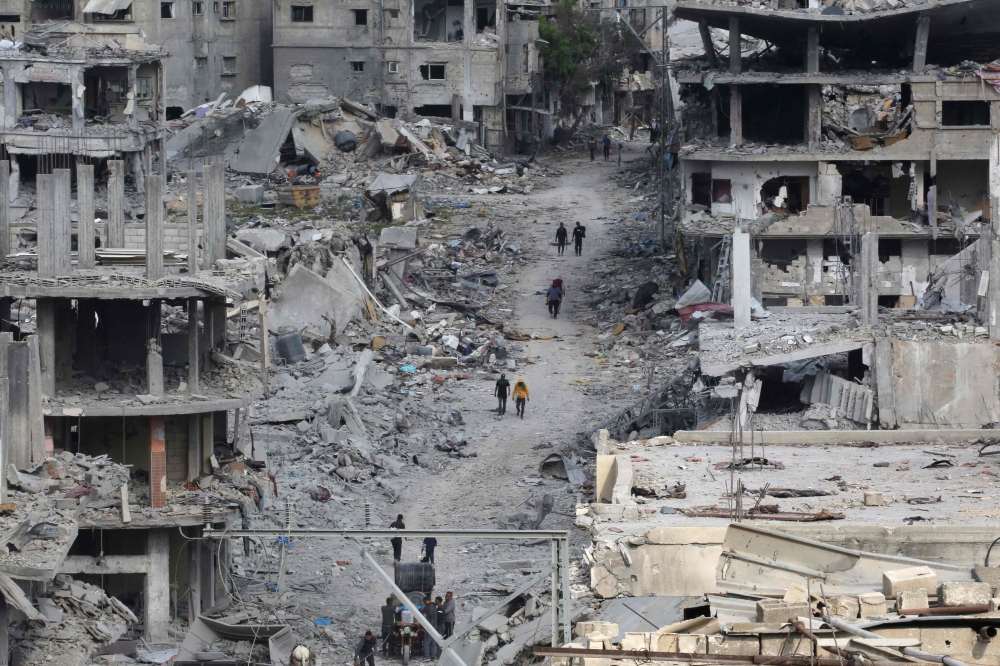 Palestinians walk past damaged buildings in Khan Yunis. — AFP