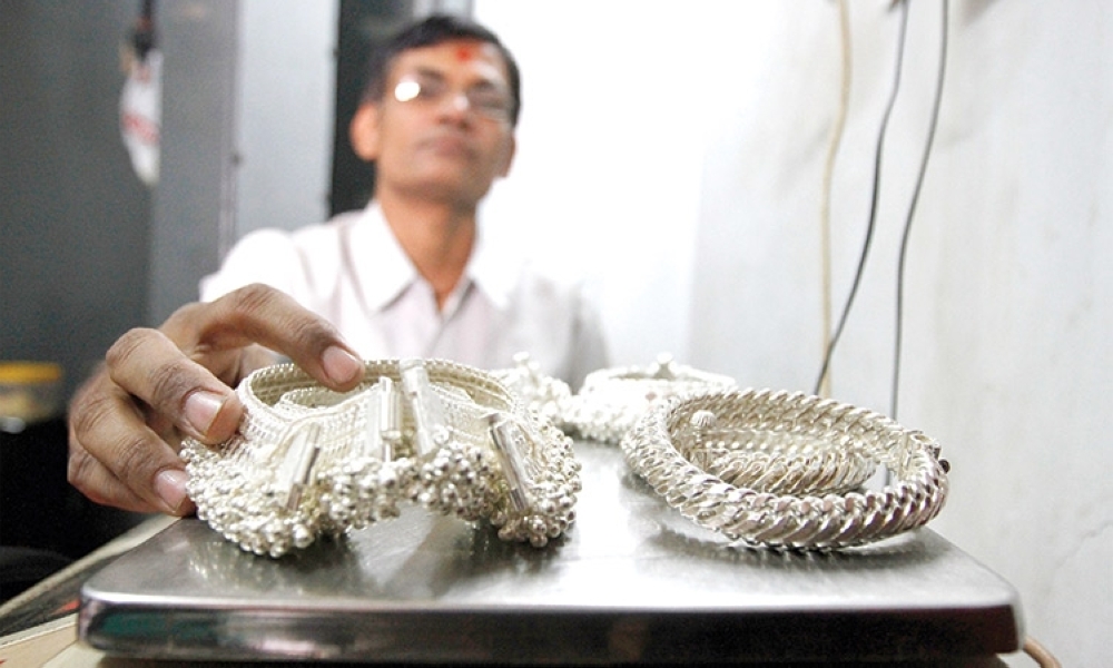 A silver trader weighs his silver ornaments inside his shop in the western Indian city of Ahmedabad, India. —Reuters 