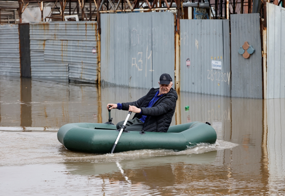 A man rows in an inflatable boat amid flooding in the city of Orenburg, Russia. - Reuters