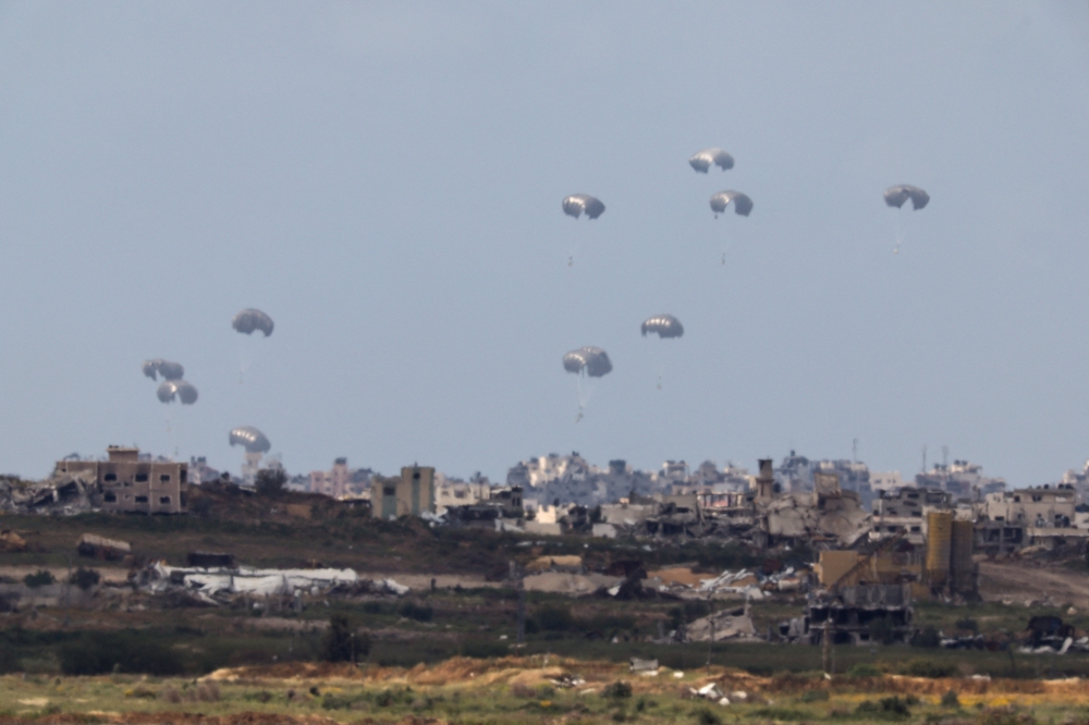 Humanitarian aid falls through the sky towards the Gaza Strip after being dropped from an aircraft, amid the ongoing conflict as seen from Israel. - Reuters