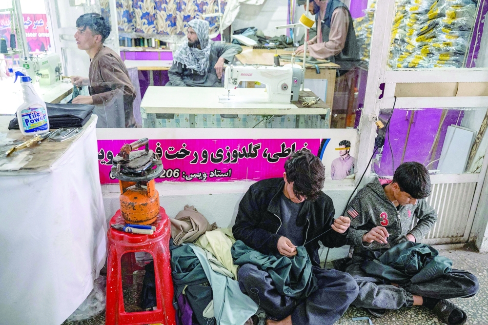 Afghan youth (front) sew clothes ahead of Eid al-Fitr, which marks the end of the Muslim holy fasting month of Ramadan at a tailor workshop in Kabul on April 7, 2024.