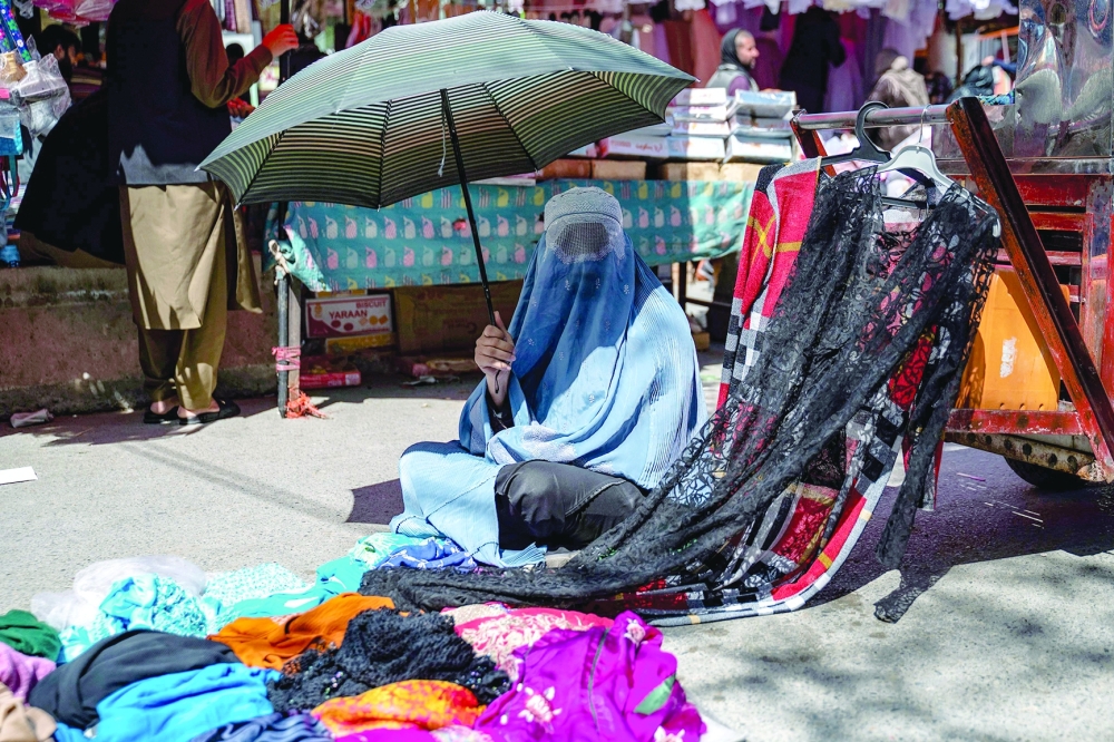 An Afghan burqa-clad woman selling clothes waits for customers at a market in Kabul on April 7, 2024, ahead of Eid al-Fitr, which marks the end of the Muslim holy fasting month of Ramadan.