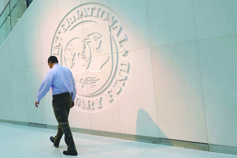 A man walks past the IMF logo at HQ in Washington. — Reuters file photo