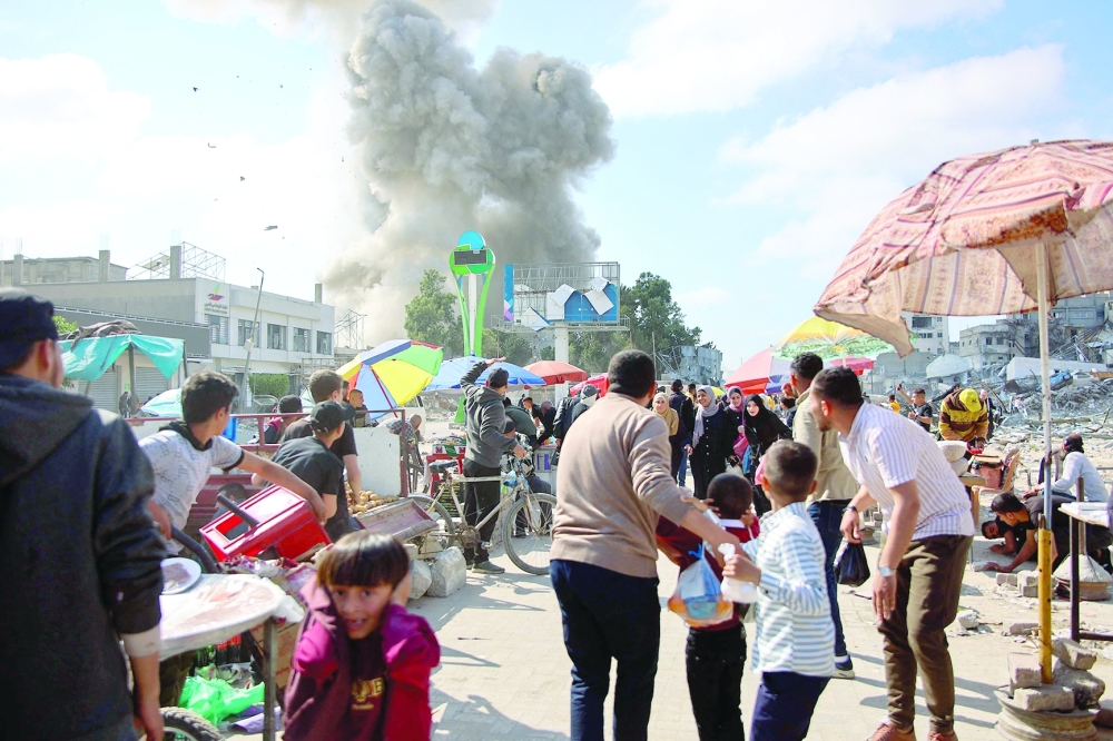 Palestinians look at smoke billowing during Israeli bombardment on the Firas market area in Gaza City on Thursday. — AFP