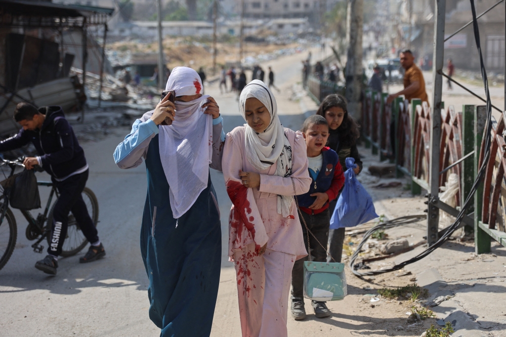 A family accompanies an injured Palestinian girl following Israeli bombardment on the Firas market area in Gaza City on April 11