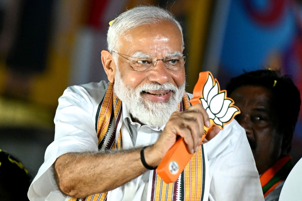 Narendra Modi, India's Prime Minister and leader of the ruling Bharatiya Janata Party (BJP) holds the party symbol during a election road show in Chennai. — AFP