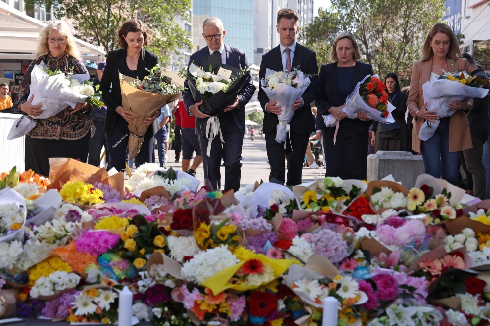 Australian Prime Minister Anthony Albanese (C) stands with officials as they prepare to leave flowers outside the Westfield Bondi Junction shopping mall in Sydney. — AFP 