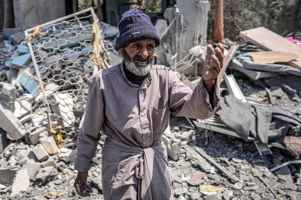 A man reacts as he walks through the rubble of a collapsed building in the central Gaza Strip. — AFP 