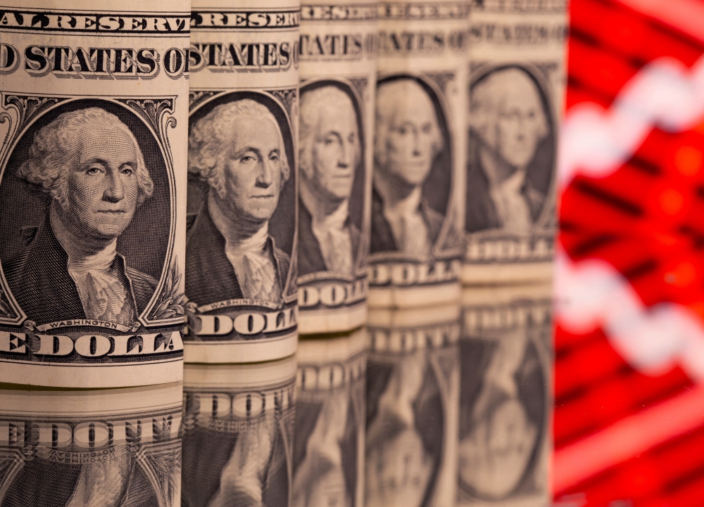 US dollar banknotes are seen in front of displayed stock graph. — Reuters