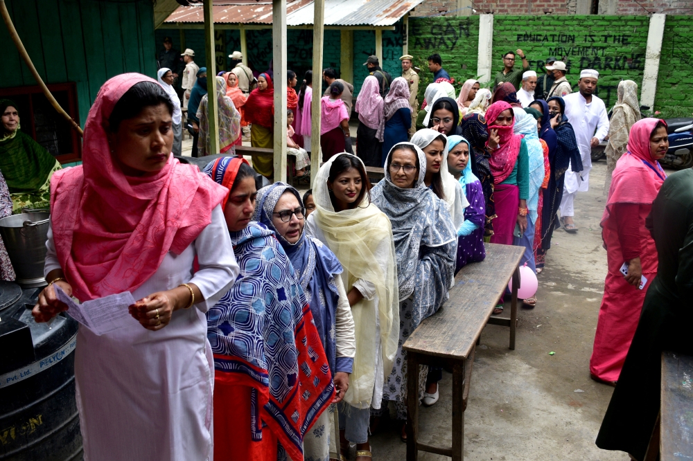 Women wait to cast their votes at a polling station during the first phase of the general election