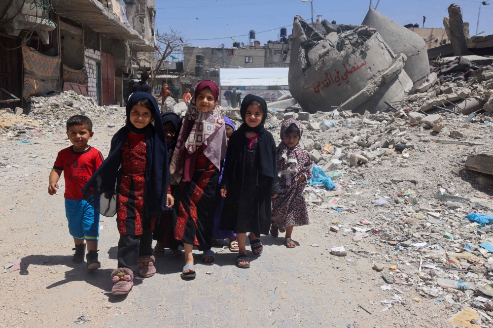 Palestinian children walk next to the ruins of Al-Farouq Mosque, destroyed during Israeli bombardment
