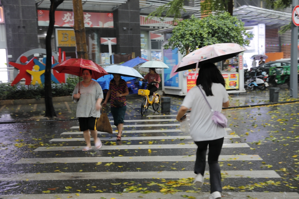 Pedestrians, holding umbrellas, cross a street amid a rainstorm in Shenzhen, Guangdong province, China — Reuters 
