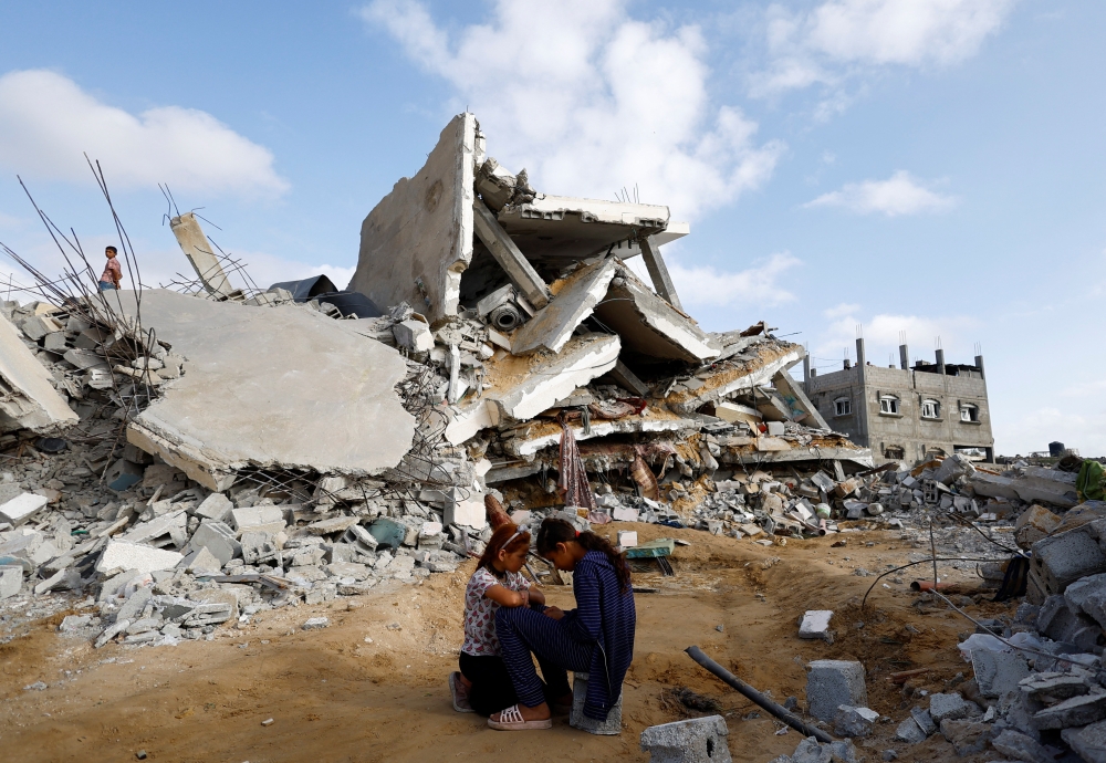 Palestinian children sit next to the site of an Israeli strike on a house, in Rafah. — Reuters 
