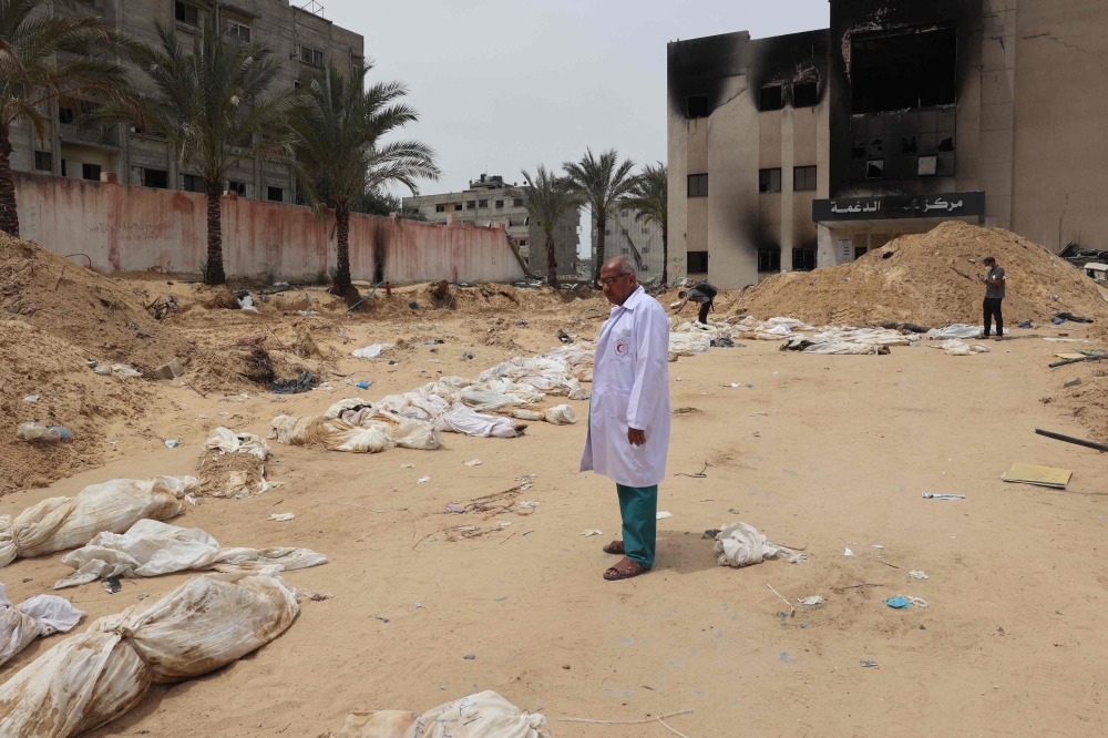 A doctor stands near bodies lined up for identification after they were unearthed from a mass grave found in the Nasser Medical Complex in the southern Gaza Strip 