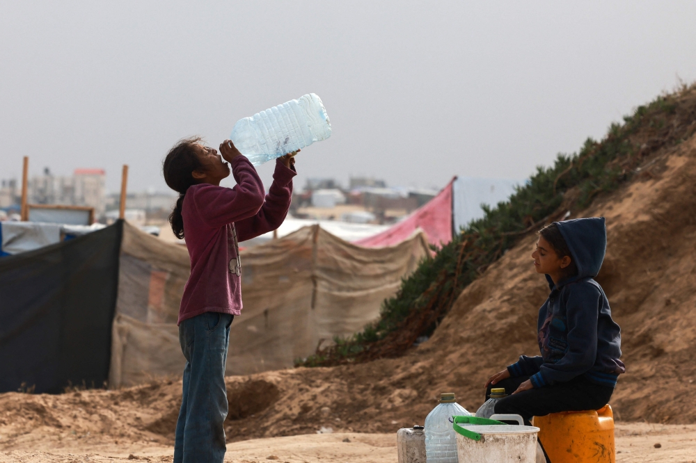 Displaced Palestinian children wait for a water supply tank to fill their containers amid soaring temperatures at a tent camp in Rafah