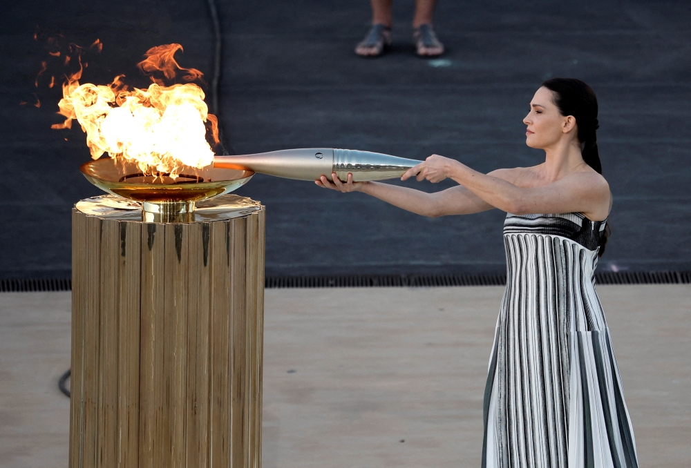 Greek actress Mary Mina, playing the role of High Priestess holds an Olympic torch by the cauldron during the handover ceremony in Athens on Friday